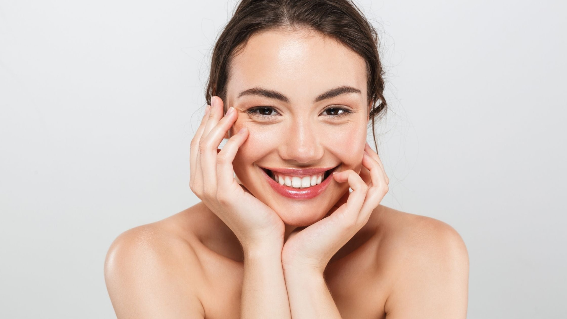 Patient smiling with hands framing her face